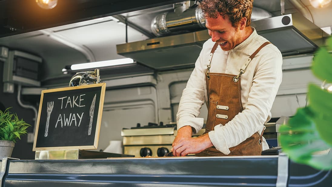 food truck worker with 'TAKE AWAY' sign on counter