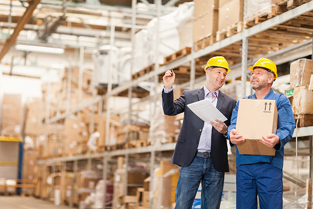 warehouse workers with boxes and documents among storage shelves